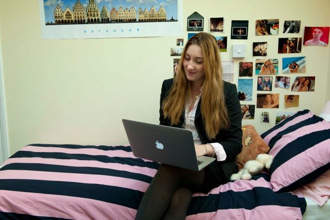 High school student working from laptop in bedroom in boarding house of a UK private boarding school in England